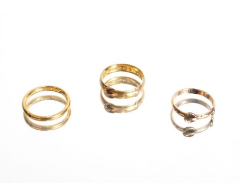 A 22ct gold wedding band, approximately 3.5gms, ring size N; a 22ct gold buckle ring, 4.2gms, ring size O; and a yellow metal