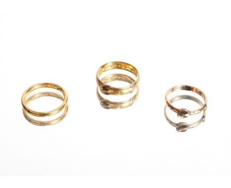 A 22ct gold wedding band, approximately 3.5gms, ring size N; a 22ct gold buckle ring, 4.2gms, ring size O; and a yellow metal