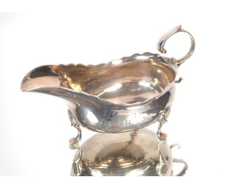 A George II Newcastle silver cream jug, maker probably John Langlands, having serrated border, flying C scroll handle raised 