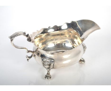 A George III silver sauce or gravy boat having serrated border, acanthus scroll handle, raised on lion mask and claw feet by 