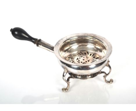 A George III silver warming dish raised on scrolled legs with turned, ebonised handle.  Maker Alexander Johnstone, London 176