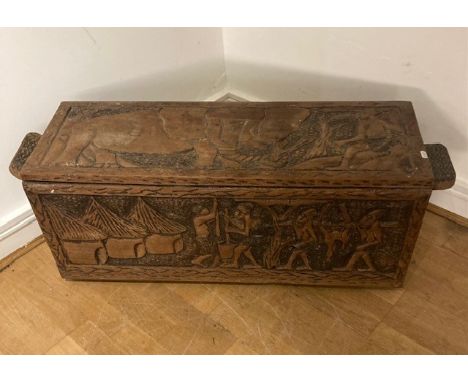 An African five plank trunk or bedding chest, richly carved to all sides with narrative panels of figures hunting, within geo