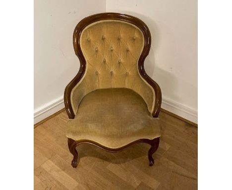 A Victorian walnut framed button back salon chair, having carved surround with yellow velvet upholstery, raised on cabriole l