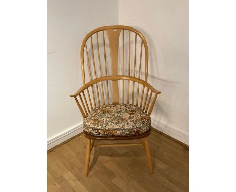 An Ercol beech and elm high back armchair/elbow chair, having spindle back with splayed armrests, raised on splayed legs unit