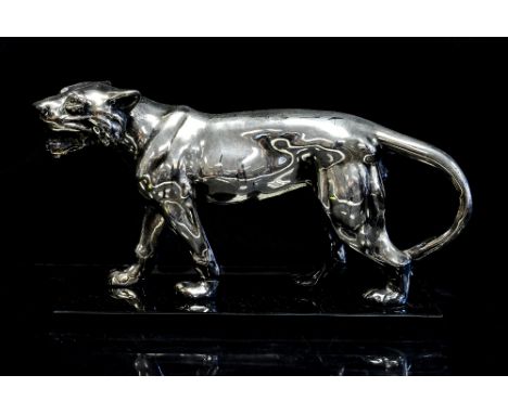An Art Deco chrome figure of a tiger on  black glass base, 19cm long