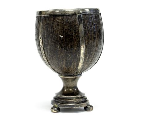 An Arts and Crafts silver mounted coconut cup, the bowl interior gilded, with strapwork decoration, on a stepped pedestal bas