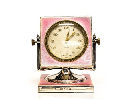 An Art Deco silver and enamelled bedside timepiece, pink guilloche enamel, the revolving square movement case supported in a 