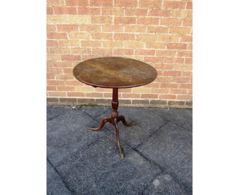 A GEORGE III TILT TOP OAK OCCASIONAL TABLE the circular top 64.5cm diameter, on turned baluster tripod support 69.5cm high