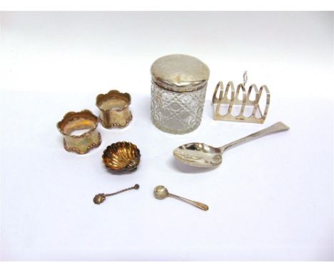 A COLLECTION OF SILVER ITEMS comprising; a pair of napkins rings; a shell salt with a spoon; a toastrack; a Gerogian table sp