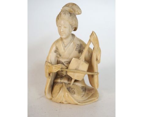 JAPANESE CARVED IVORY OKIMONO OF A GEISHA MUSICIAN
playing a shamisen while kneeling, dressed in a kimono, 9.2cm high 