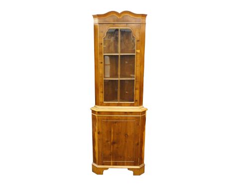 YEW WOOD CORNER DISPLAY CABINET
the shaped moulded top above a glazed beaded door opening to reveal a shelved interior, the l