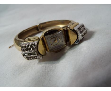 An unusual gold-plated lady's wristwatch, the solid bracelet hinging open to adorn the wrist, beset with marcasite and other 