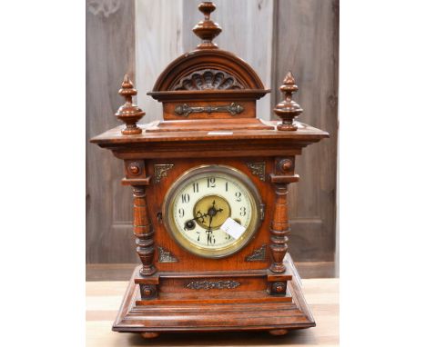 A late Victorian mahogany 8 day ornate mantle clock, decorative top with finials and Arabic numerals, sitting on bun feet.