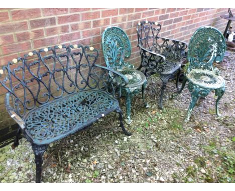 An ornate two seater cast garden bench along with a matching armchair and two other garden chairs.