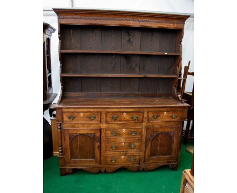 A George III oak dresser and rack, the moulded cornice above a crossbanded frieze and two fixed shelves, the base with an arr