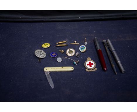 A collection of vintage pens, badges and fruit knife.