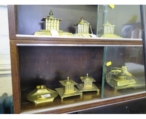 A set of three brass inkwells, possibly by Adolph Frankau & Co., each of square form with mask and scroll borders and slightl
