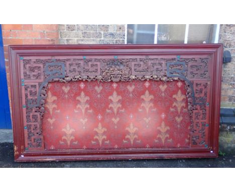 A CHINESE CARVED AND LACQUERED FRAME previously used as a headboard, with a cushioned central panel, within and pierced borde