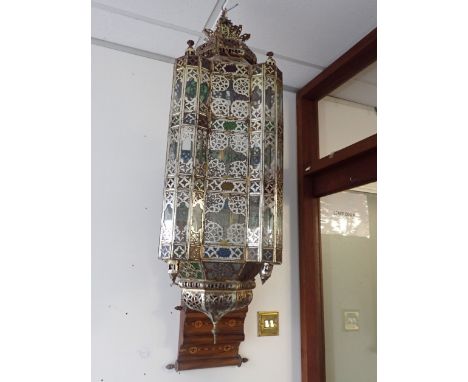 A MOROCCAN STYLE BRASS FRAMED GLAZED HANGING LANTERN 20th century, the pierced domed surround with coloured glass panels, con