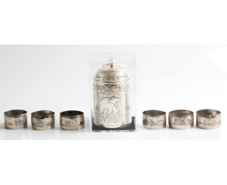 A white metal tea caddy depicting elephants, with spoon, together with six white metal napkin rings depicting camels and boat