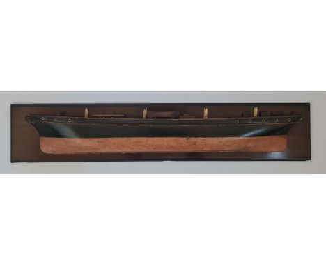 A 19th century folk art half block ship model, the detailed deck above the black and red painted hull, the whole a mahogany p