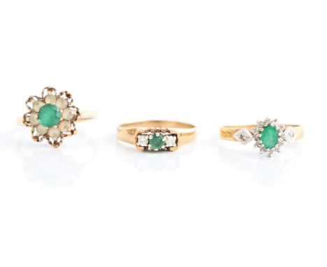 Three hallmarked 9ct yellow gold rings, to include an emerald and diamond cluster, a three stone emerald and diamond, and a g