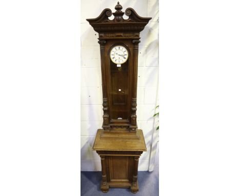 A late 19th century oak cased Vienna wall timepiece with cupboard below, with single train movement, the two piece enamel cir