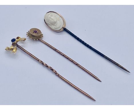 A 15ct gold tie pin set with a ruby along with a 15ct gold bow shaped pin and a 15ct cameo version (pin not gold)
