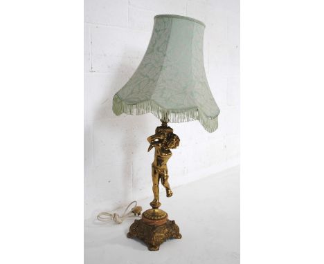 A brass table lamp in the form of a cherub, with shade