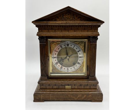 An oak cased mantle clock with carved decoration, column detail and gilt brass dial