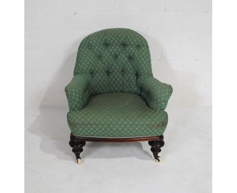 A Victorian button-back armchair, raised on turned legs with ceramic castors
