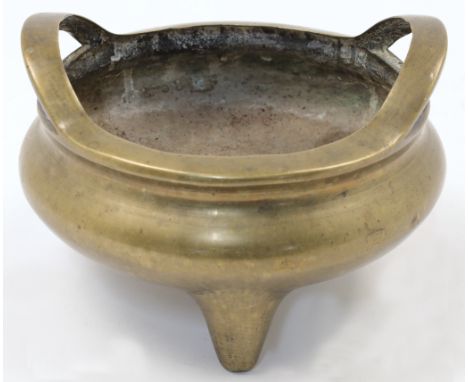 A Chinese bronze censer, early 20th century, cast in circular form with twin high loop handles and three feet, with relief of