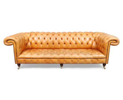 A Chesterfield three seat sofa, late 20th century, with tan leather button back upholstery, raised on turned feet to brass ca