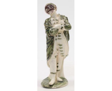 An Italian terraglia figure from the Commedia dell’Arte, c.1800, decorated in green and manganese, modelled with his arms fol