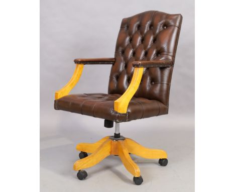 A brown leather desk chair, in the George III style, 21st century, with button back upholstery, on splayed legs and castorsCo