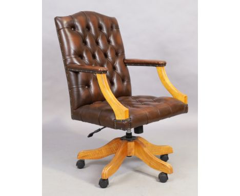 A brown leather desk chair, in the George III style, 21st century, with button back upholstery, on splayed legs and castorsCo