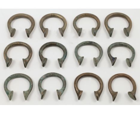 Twelve West African bronze Manilla currency bangles, approx. 5.9cm wide (12)&nbsp;&nbsp;