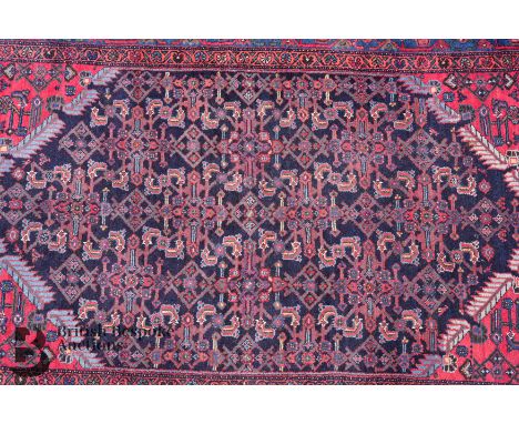 A Turkish wool carpet, a geometric border enclosing a field of blue medallion, navy, cornflower blue, burgundy and pink colou