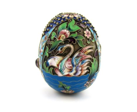 A Russian silver-gilt and enamel egg, decorated with swans on a lake with foliate scroll decoration, rope-work borders, purpl