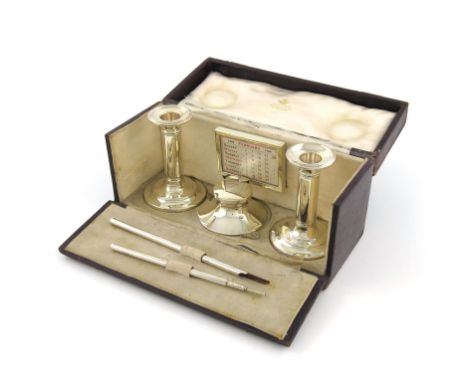 By Asprey, a silver desk set, Birmingham and London 1908, comprising: a pair of candlesticks, an inkwell, a calendar, and a p