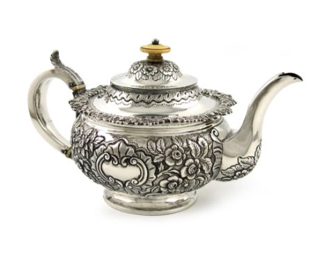 λA George IV Irish silver tea pot, maker's mark of M.F, Dublin 1822, circular form, embossed foliate decoration on a matted b