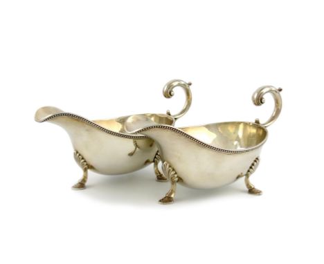 A pair of silver sauce boats, by William Hutton & Sons Ltd, Sheffield 1934, oval form, with a bead border, scroll handles, on