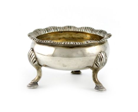 A mid-18th century silver salt cellar, makers mark worn, ?R, London, circular form, gadroon border, on three shell capped hoo