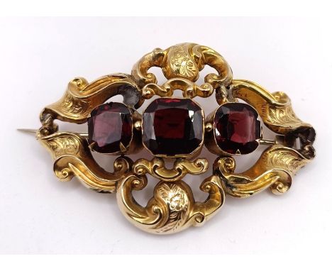 A late 19th century yellow coloured metal and red stone brooch, in a vintage jewellery box