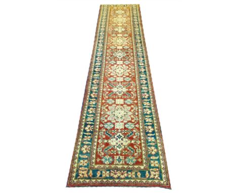FINE KAZAK RUNNER, 360cm x 83cm, row of stylised medallions on a ruby field within ivory guard stripes and a repeat rosette m