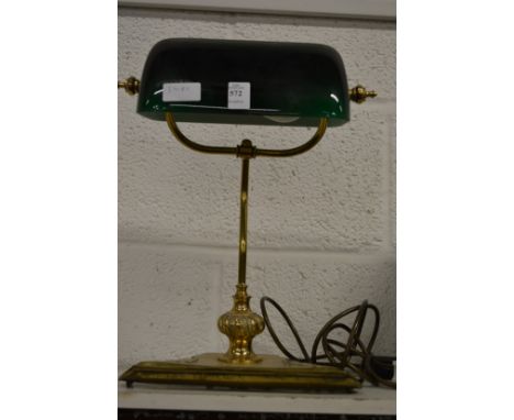 A brass desk lamp with green glass shade.