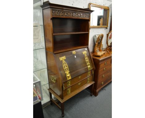 An Art Nouveau mahogany bureau bookcase with carved frieze, open shelves above a drop-flap, two drawers, all with ornate bras
