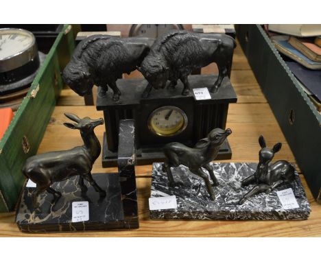 A small mantle clock mounted with bison together with a bookend and another item.