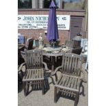 A good circular hardwood garden table with six armchairs, a parasol and a granite lazy Susan.