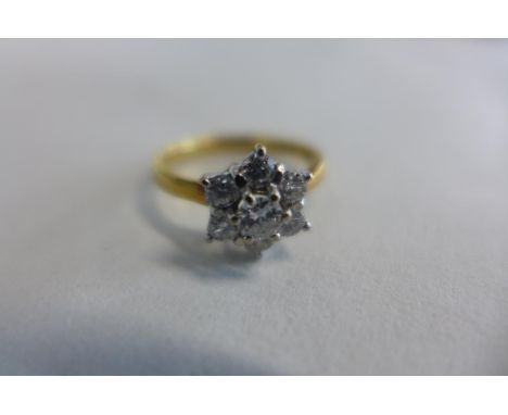 An 18ct yellow and white gold diamond daisy cluster ring, the central brilliant cut diamond is set in six claws and is surrou